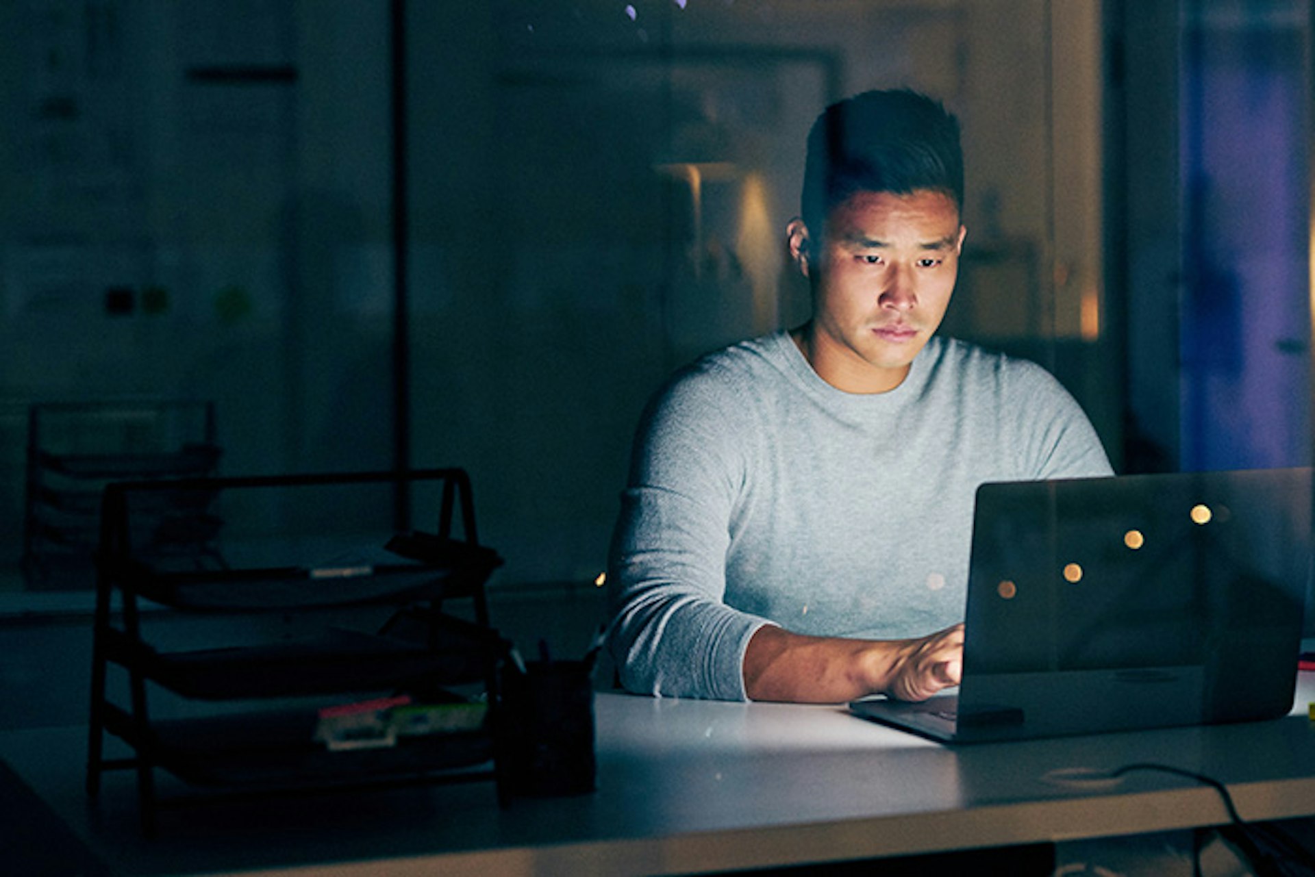 Hombre iluminado por una laptop en una habitación oscura